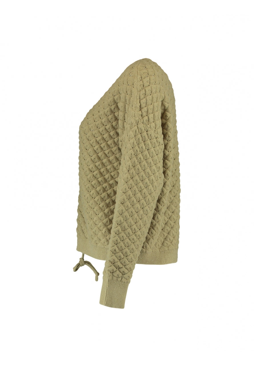 Jersey con dibujo calada y ajustable en cintura para poder acortarlo al gusto. Composición: 43% Poliacrílico, 29% Poliéster y 28% Poliamida. Se recomienda lavar a mano o en lavadora hasta 30º. No usar lejía, planchar suavemente del revés hasta 110º y no usar secadora.
