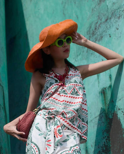 Camiseta sin mangas de Señoretta Streetwear con escote en pico y estampado geométrico de inspiración mediterránea en tonos verde y rojo sobre fondo claro. Su diseño fluido y ligero la convierte en una prenda fresca y cómoda, ideal para los días más cálidos. El corte recto estiliza la silueta y permite combinarla fácilmente con pantalones a juego, shorts o jeans para crear looks casuales con personalidad. Perfecta para outfits veraniegos, tanto de día como de tarde, aportando un toque original. Escote en V y