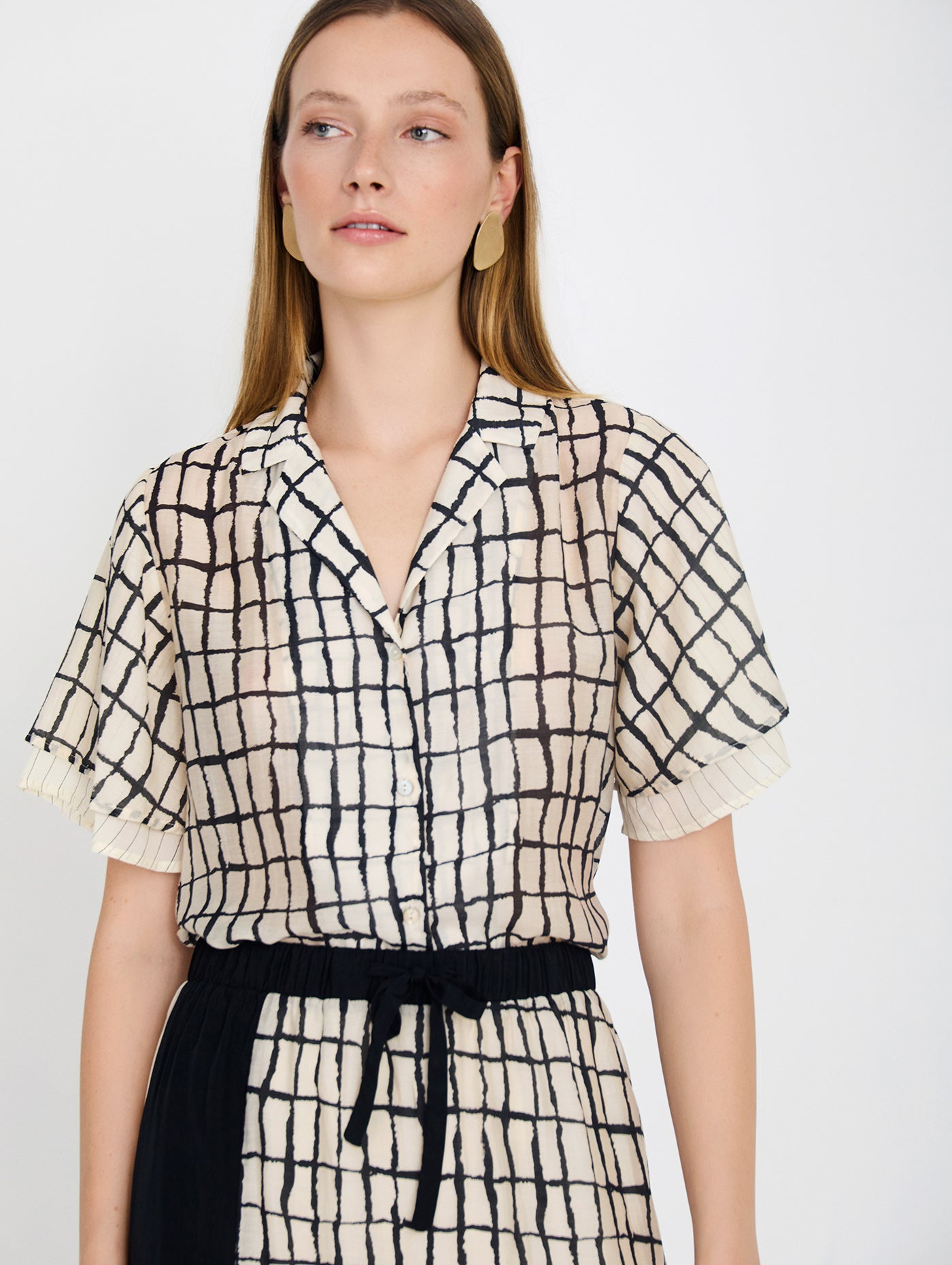 Camisa con tejido fluido de tencel con estampado de cuadros. Cuello solapa y cierre frontal con botones. Manga corta con doble capa de tejido.

Composición: 80% Tencel y 20% Nylon.

Se recomienda lavar a mano o en lavadora hasta 30º. No usar lejía, planchar suavemente del revés hasta 110º y no usar secadora.